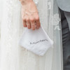 Bride holding her dainty white lace wedding handkerchief that is embroidered with a custom message in grey,