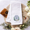 Custom embroidered golf towel for bride or groom. White gold towel is embroidered with their wedding crest. Shown with golf tees and flowers on a woven mat for decoration.