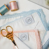 Handkerchiefs made in the USA by The Handkerchief Shop. Handkerchiefs are shown in white fabric with blue and pink lace with matching thread.