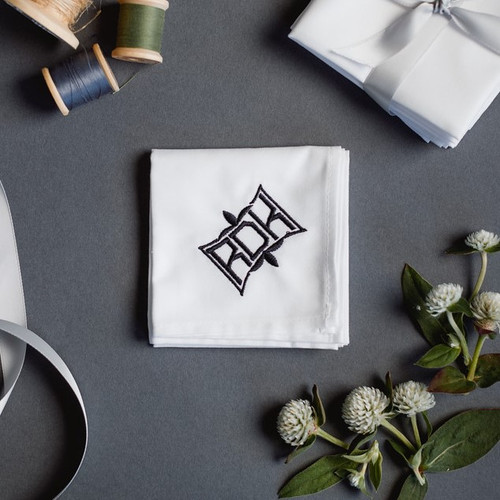 Men's monogrammed white handkerchiefs with fleur embroidered monogram style.  Handkerchief has black embroidery.
