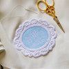 Monogrammed wedding dress patch in powder blue with white embroidery thread. Needle and thread for sewing into dress and scissors.