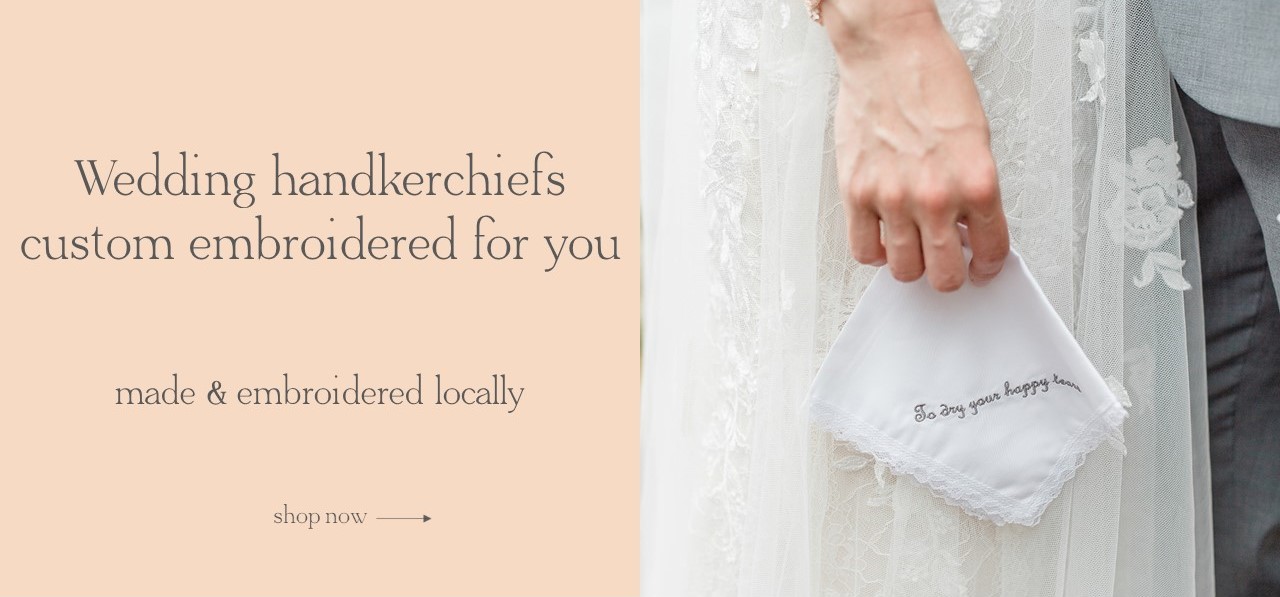 Bride holding custom embroidered wedding handkerchief in white with white lace, gray embroidery thread.